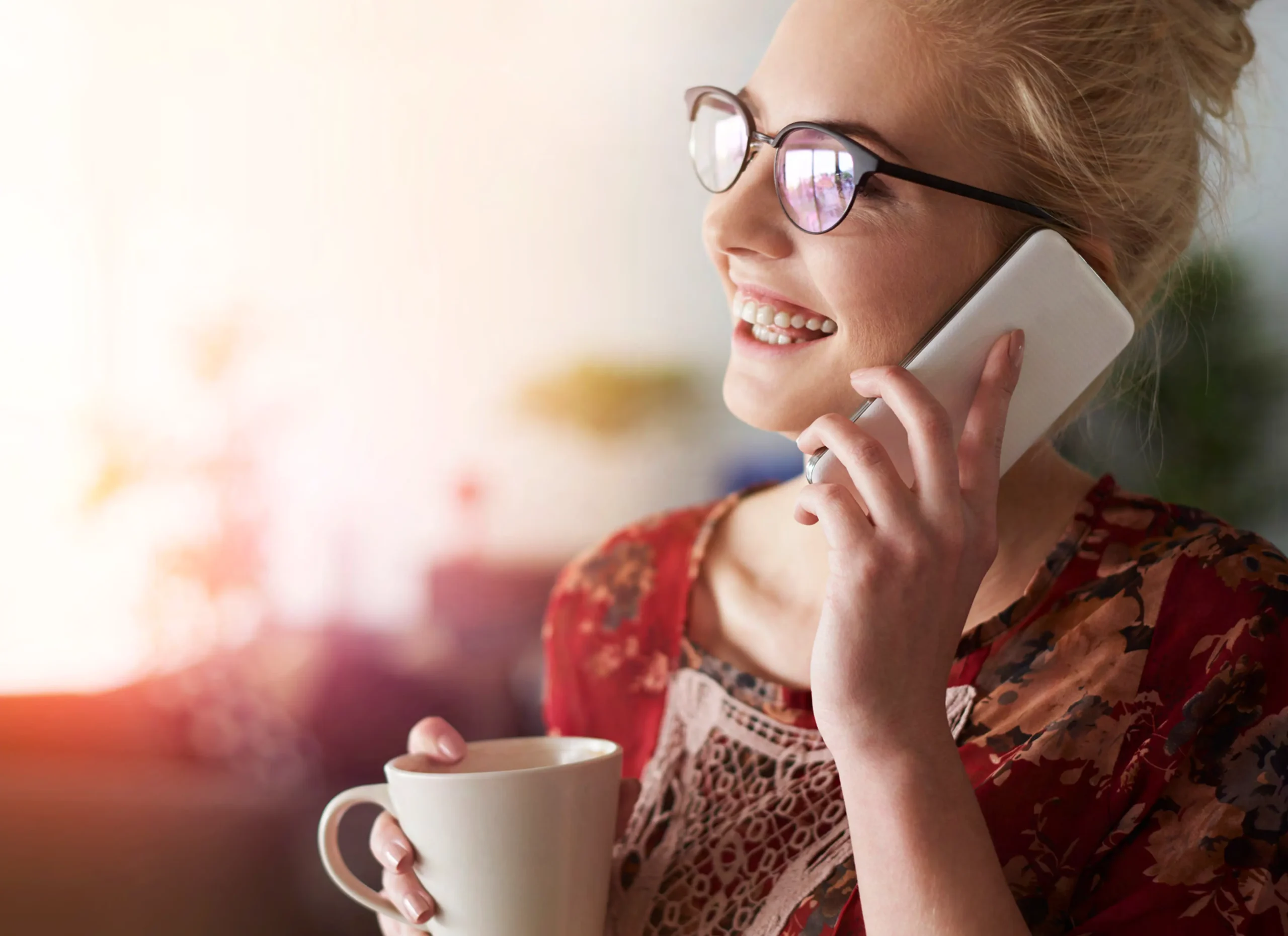 Woman on phone holding a mug.